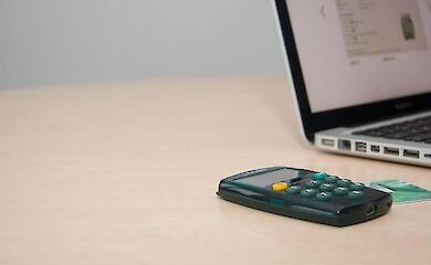 Calculator, bank card and a laptop on the desk.