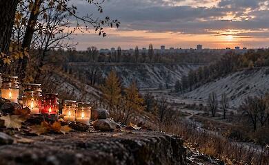 Memorial candles and stones against an autumn ravine at sunset.