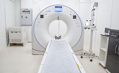 A CT scanner with a sliding table in an empty medical imaging room