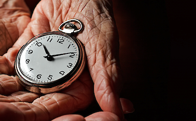 A pocket watch in an elderly person’s hands